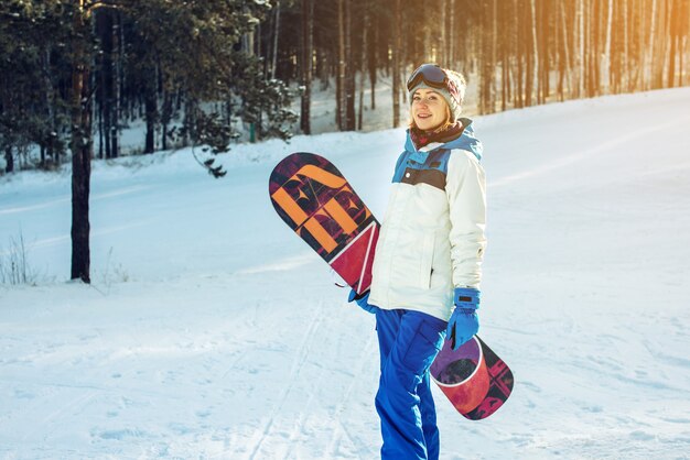 Snowboarder femelle avec snowboard parmi les arbres