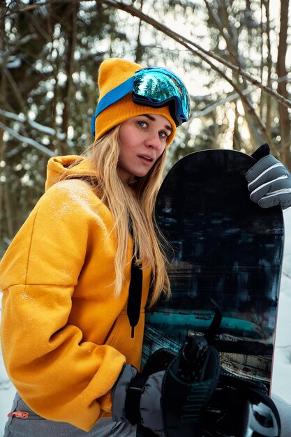 Snowboarder femme en costume lumineux dans des lunettes de sport est titulaire d'un snowboard. Sports extrêmes. Loisirs.