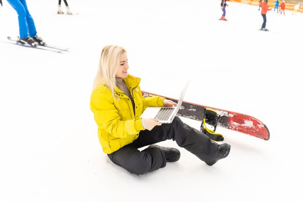 Snowboarder femme travaillant sur ordinateur portable dans les montagnes d'hiver