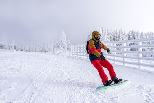 Snowboarder glissant à travers la pente dans une station de montagne