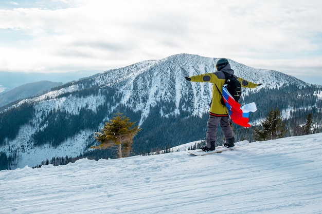 Snowboarder homme avec le drapeau de la slovaquie sur la pente de la station de ski