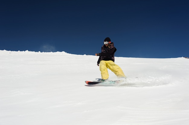 Snowboarder patine dans la neige contre le ciel bleu