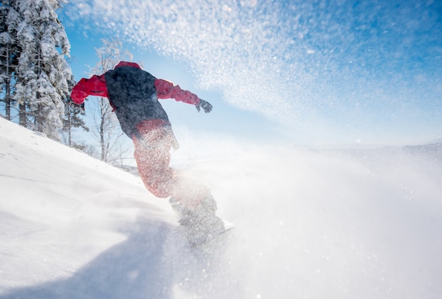 Snowboarder sur la pente lors d'une journée d'hiver ensoleillée dans les montagnes.