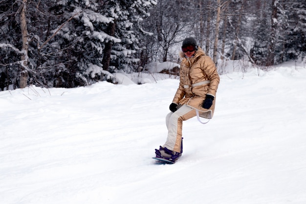 Snowboarder professionnel femme en vêtements de sport lumineux et tenue de ski alpin dans les hautes montagnes ensoleillées enneigées. Flou, flou, objet en mouvement