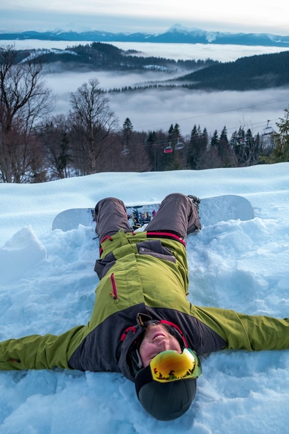 Snowboarder profitant de la vue sur le coucher du soleil au-dessus des montagnes