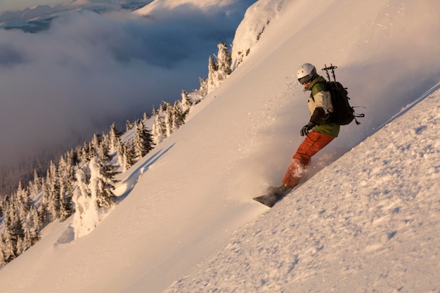 Snowboarder se déplaçant dans la poudreuse de neige profonde en descente sur une pente raide dans les montagnes