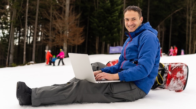 snowboarder tapant sur l'ordinateur portable dans les montagnes hiver