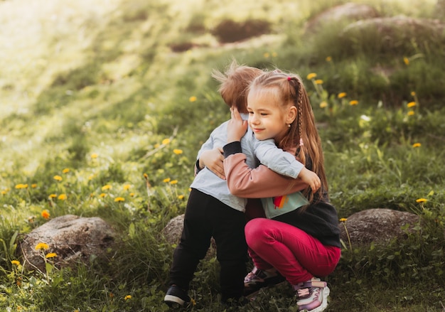 La sœur aînée embrasse son petit frère en été dans le parc