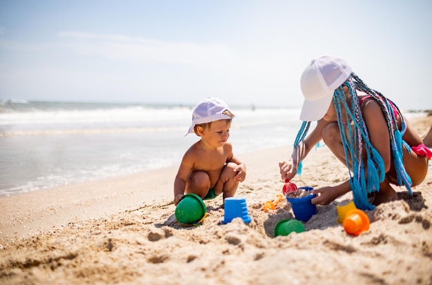 Sœur aînée jouant avec son jeune frère échoué près du rivage pendant les vacances d'été