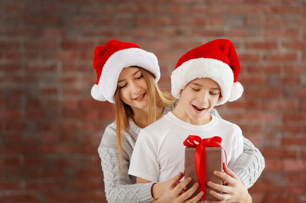 Soeur et frère heureux avec boîte-cadeau sur fond de mur de briques