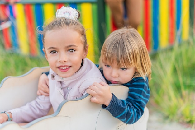 Soeur et frère heureux s'asseyant dans un jeu de terrain de jeu