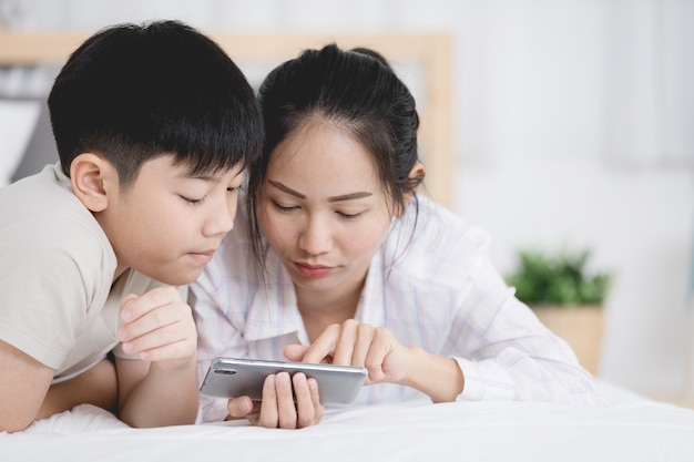 Soeur et frère regardant dans le téléphone sur le lit.