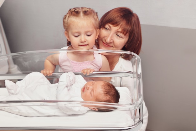 La soeur et la grand-mère regarde un nouveau-né dans la salle d'hôpital