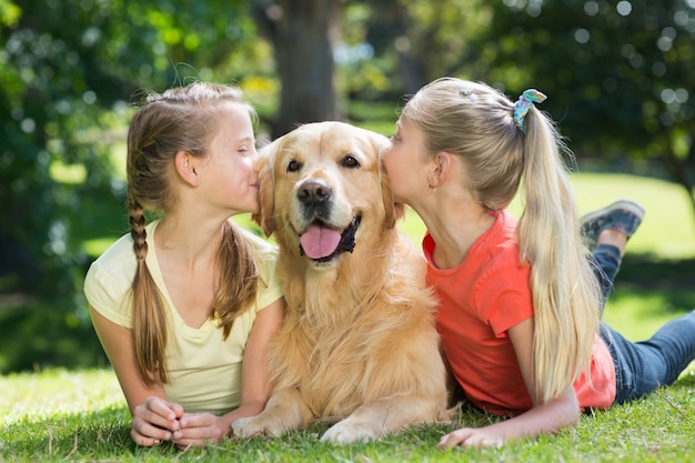 Sœurs embrassant leur chien dans le parc