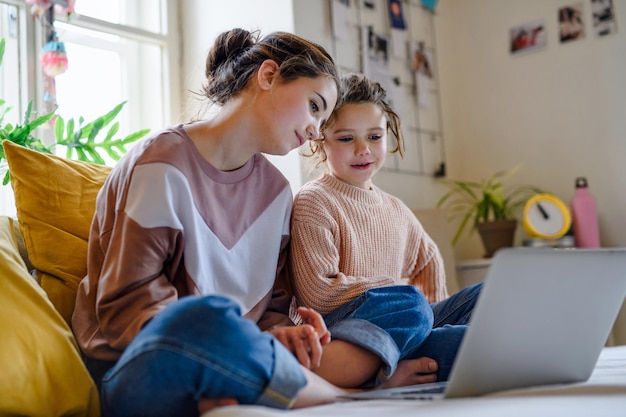 Soeurs heureuses à l'intérieur avec ordinateur portable à la maison, regardant un film. Notion de verrouillage.