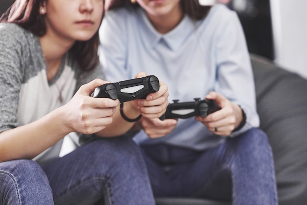 Les sœurs jumelles jouent sur la console. Les filles tiennent des joysticks dans leurs mains et s'amusent