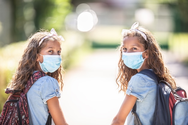 Sœurs jumelles avec masque facial de retour à l'école pendant la quarantaine COVID-19.