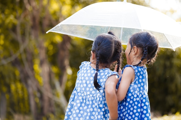 Sœurs avec parapluie s&#39;amuser en jouant sous la pluie