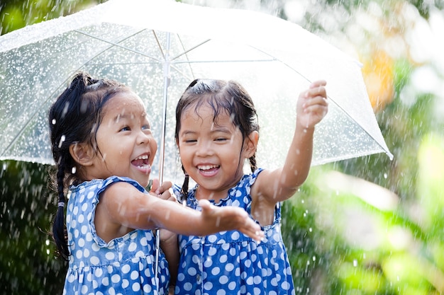 Sœurs avec parapluie s&#39;amuser en jouant sous la pluie