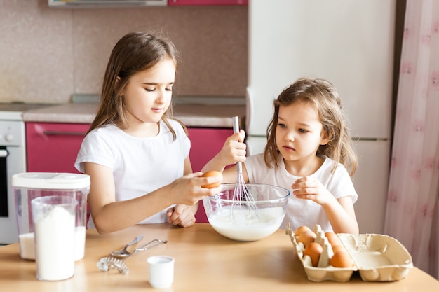 Les sœurs préparent le petit déjeuner, les pâtisseries, mélangent la farine, le lait, les œufs, les crêpes dans un bol, les enfants aident la mère, le petit déjeuner en famille, la cuisine