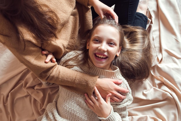 Sœurs s'amusant sur fond textile de couleur beige