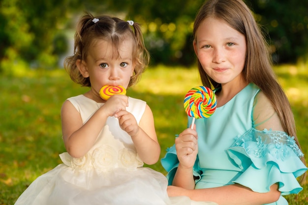 Sœurs avec des sucettes sucrées dans la nature en été dans le parc