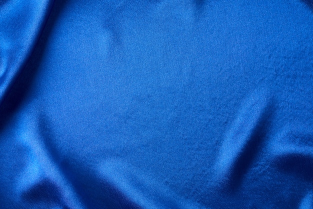 Soie bleue avec plis. Texture abstraite de la surface satinée ondulée