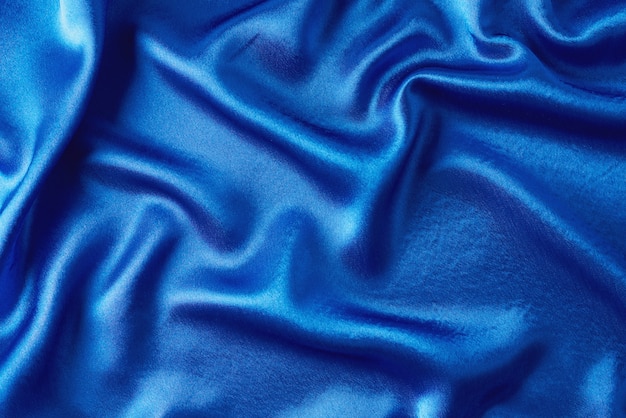 Soie bleue avec plis. Texture abstraite de la surface satinée ondulée