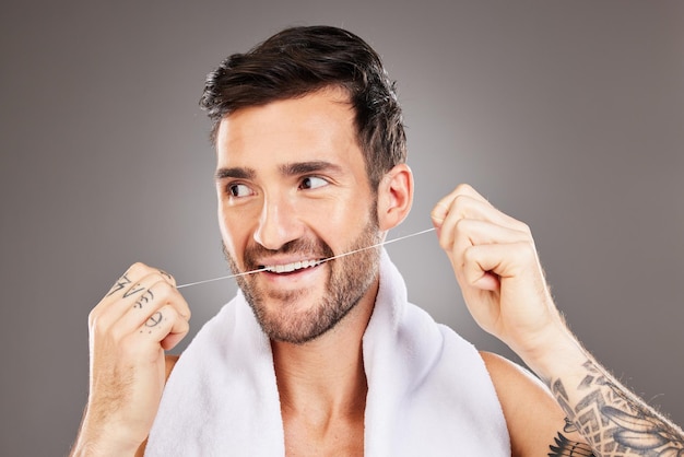 Soie dentaire et homme de nettoyage en studio isolé sur fond gris Soins bucco-dentaires santé dentaire et modèle masculin heureux d'Australie soie dentaire pour le bien-être des gencives ou une hygiène buccale saine