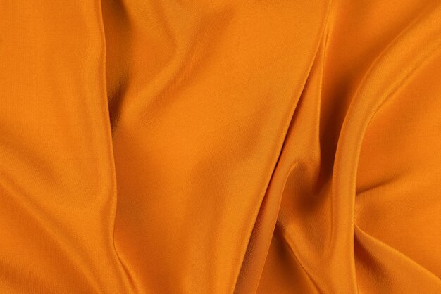 La soie dorée ou la texture de tissu de luxe en satin peut être utilisée comme fond abstrait