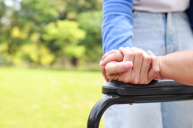 Un soignant serre la main d'une personne âgée assise sur un fauteuil roulant Concepts de soins infirmiers pour prendre soin des personnes âgées soins de santé centre de réadaptation pour personnes âgées enfant prenant soin de la vieille mère