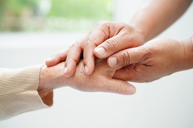 Soignant tenant la main d'une femme âgée asiatique aide et soins aux patients à l'hôpital