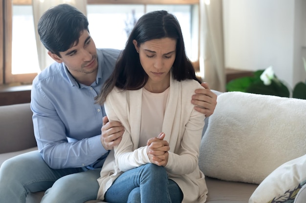 Soin jeune mari toucher étreindre réconfort bouleverser femme aimée se sentir déprimé ou anxieux au sujet des relations problèmes homme aimant demander pardon faire la paix se réconcilier avec sa femme après avoir trompé