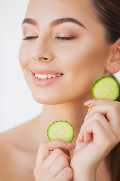 Soin de la peau. Belle jeune femme avec des concombres sur les yeux