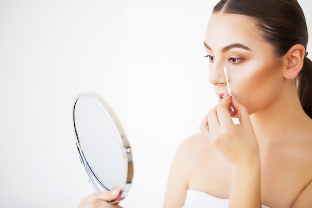 Soin de la peau. Portrait de jeune femme sexy avec une peau saine et fraîche à la recherche dans le miroir à l'intérieur