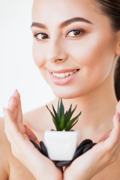 Soin de la peau. Visage de femme de beauté avec une peau saine et plante verte