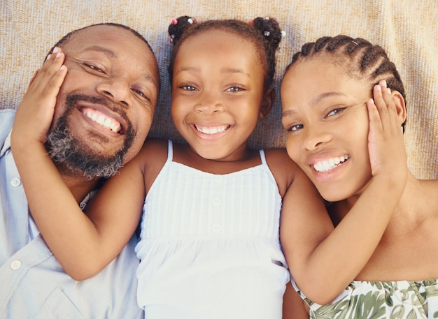 Les soins d'amour et les liens heureux de la famille noire se détendent et se reposent ensemble à la maison d'en haut Portrait de parents souriants appréciant le temps avec leur enfant montrant de l'affection et aimant avec leur fille
