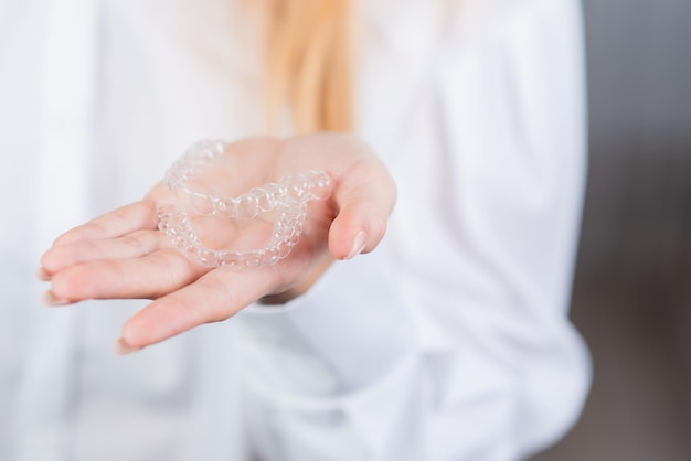 Soins dentaires Le médecin de l'orthodontiste a des gouttières dans la paume de sa main pour aligner ses dents