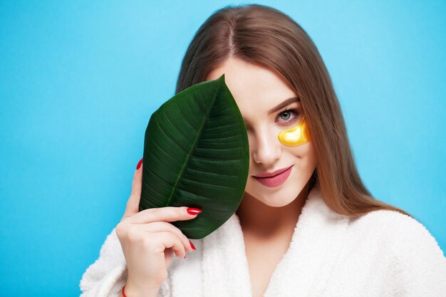 Soins du visage, jeune femme tenant une feuille verte près de la santé de la peau du visage.