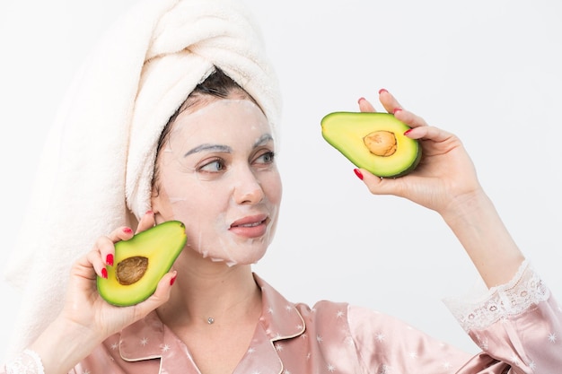 Soins du visage et soins de beauté Femme avec un masque d'avocat hydratant en feuille sur son visage isolé sur fond blanc