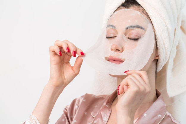 Soins du visage et soins de beauté Femme avec un masque hydratant en feuille sur son visage isolé sur fond blanc