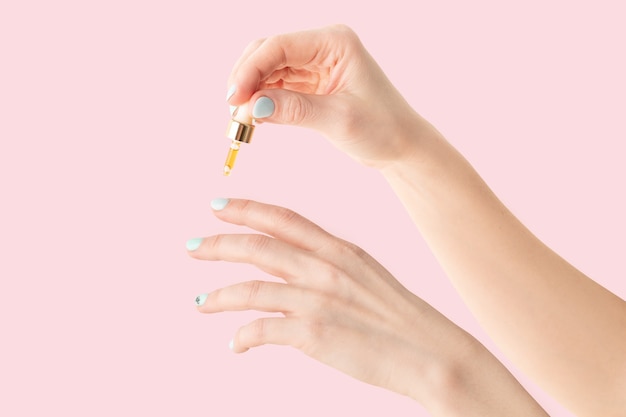 Soins des ongles, une fille dégouline d'huile avec des vitamines sur ses ongles