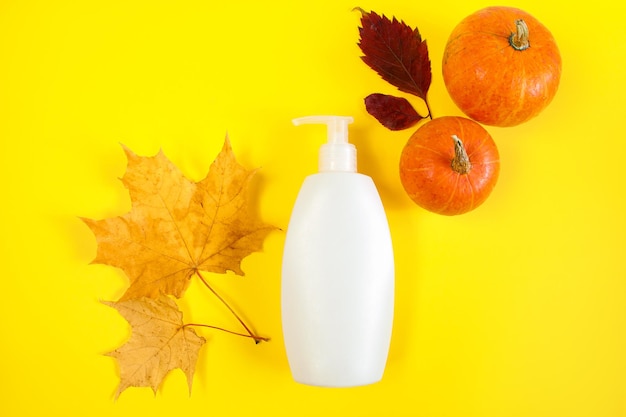 Soins de la peau d'automne Flacon cosmétique blanc et feuilles jaunes Concept minimaliste pour la présentation du produit