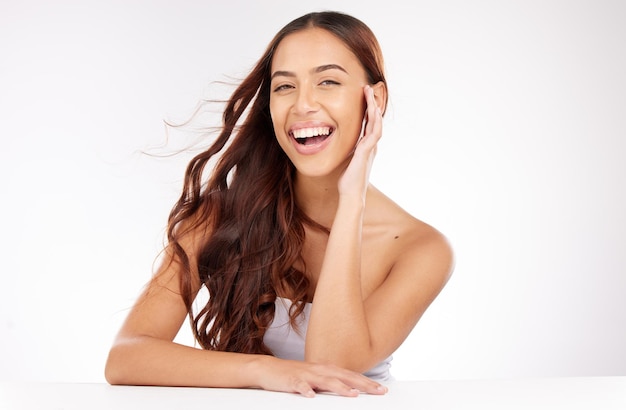 Soins de la peau de beauté et femme en studio avec des cosmétiques de soins capillaires et un maquillage naturel sur fond blanc ou espace marketing Portrait heureux et dents de jeune mannequin pour la publicité de maquette de salon de beauté