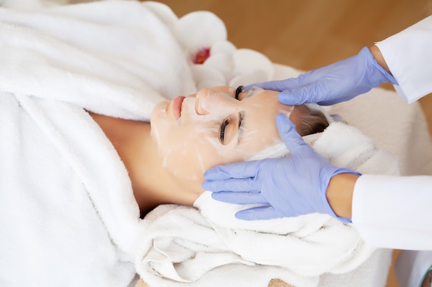 Soins de la peau, belle femme avec masque facial au salon de beauté.