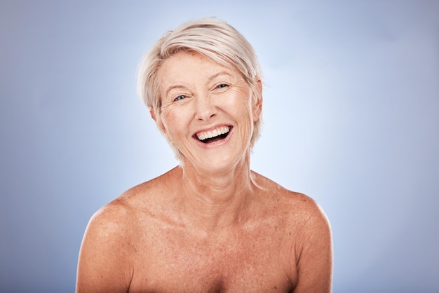 Photo soins de la peau bien-être et portrait d'une femme âgée souriante en studio sur fond bleu maquillage de beauté et vieille femme heureuse avec une peau naturelle pour les produits de beauté anti-âge dermatologie et cosmétique