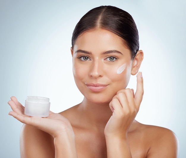 Soins de la peau du visage et femme avec un contenant de crème en studio isolé sur fond blanc Lotion de dermatologie de portrait et modèle féminin appliquent un écran solaire cosmétique ou un produit hydratant pour la santé de la peau