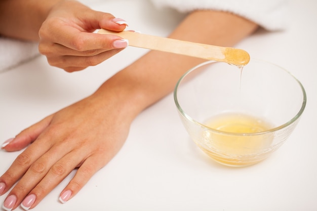 Soins de la peau, une femme applique de la cire sur sa main pour enlever les poils.