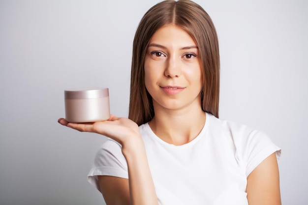 Soins de la peau, femme au visage de beauté tenant une crème pour la peau du visage.