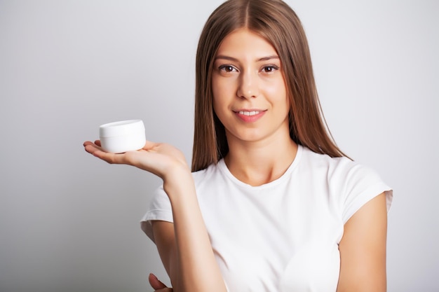 Soins de la peau, femme au visage de beauté tenant une crème pour la peau du visage.
